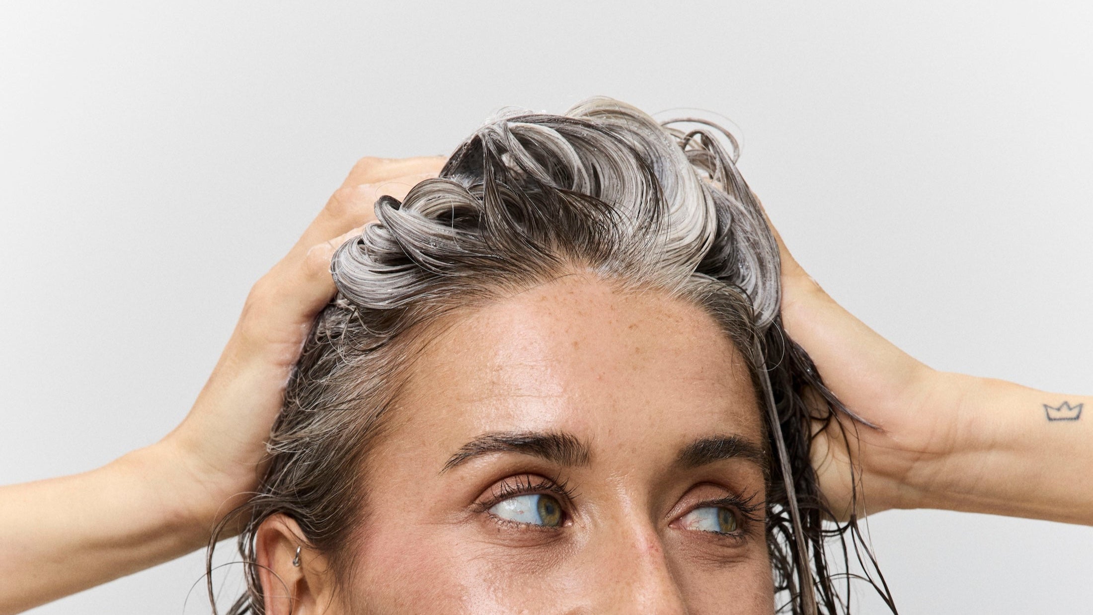 Woman with wet hair wrapped in a towel against a plain background