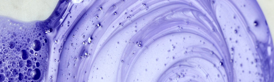 Close-up of swirling purple and white liquid with bubbles on a light background